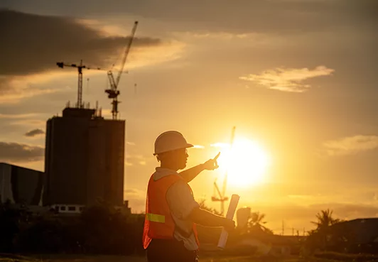 Engineer at a construction site, with sunset in the background